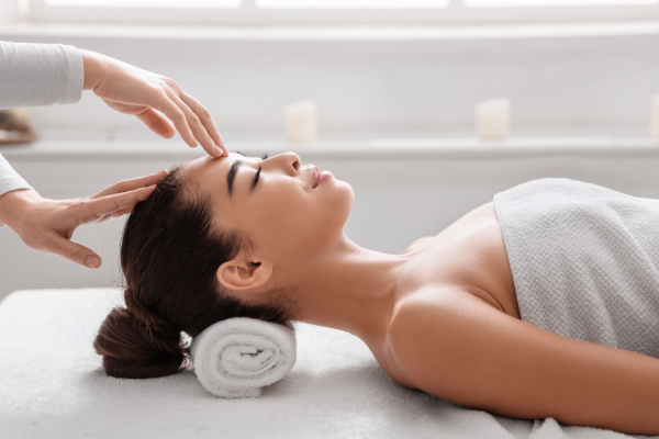 A client receiving a head massage while lying on a massage table